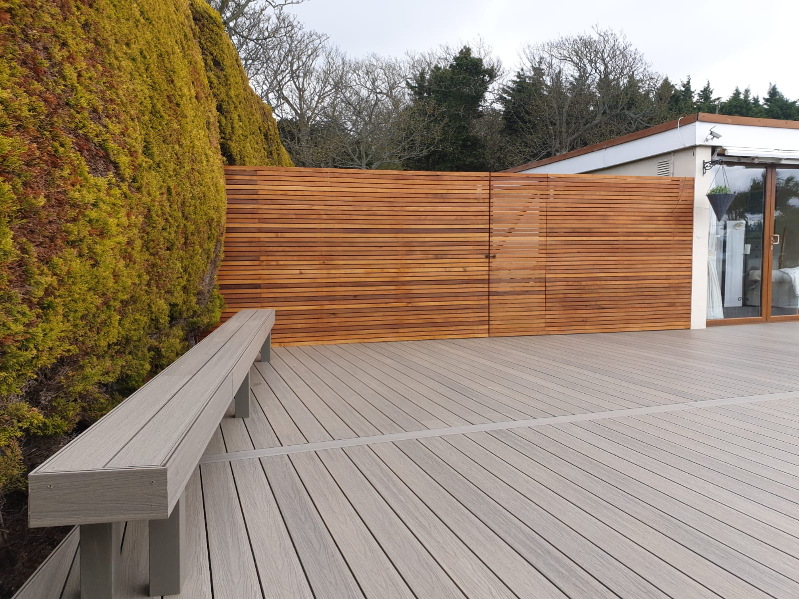 Grey composite deck with built-in bench and cedar screening